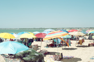 Imagen veraniega de sombrillas coloridas en una playa llena de gente frente a un mar en calma un...