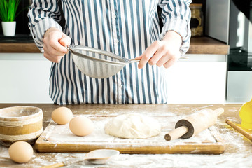 Female hands making dough on kitchen background