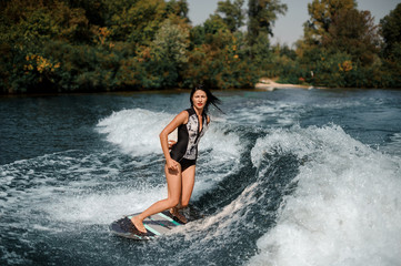 Sexy brunette girl riding on the wakeboard on the lake