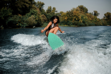Brunette girl jumping on the wakeboard on the lake