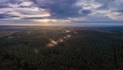 Beautfiful summer sunset over foggy european forest