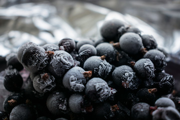 Close up of frozen black currant berries covered with hoarfrost. Selective focus