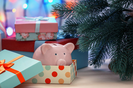 Under a Christmas tree in a holiday box we lay a piggy bank. A gift, a symbol of the new year.
