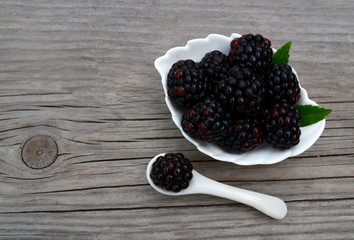 Freshly picked organic blackberries in a white bowl on old wooden table.Healthy eating,
vegan food or diet concept.Selective focus.