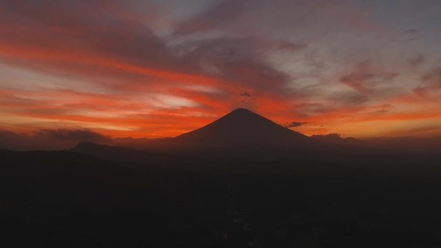 Aerial view of Volcano Mount Agung at sunset with a red orange sky, Bali, Indonesia. Conical volcano of Gunung Agung. mountain landscape. 4K, Aerial footage.