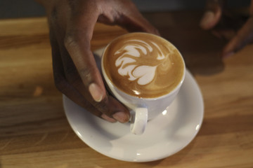 Cappuccino mit Latte Art und Männerhand 