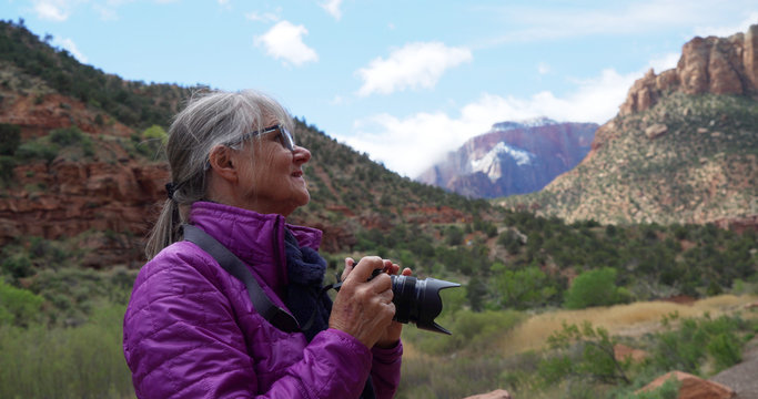 Senior female photographer taking pictures of sandstone canyon in Zion Utah