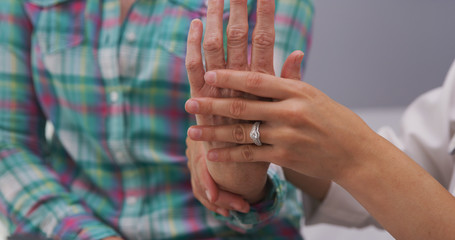Closeup of female medical doctor examining senior patients hand and wrist. Tight shot of young...