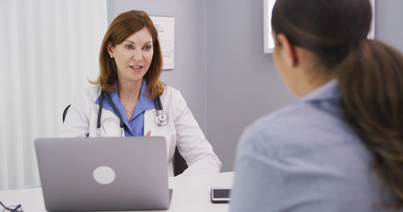 Professional caucasian doctor discussing with young female patient about issues surrounding future surgery. Young patient consulting with medical doctor over her health condition