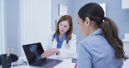 Close up of charming senior doctor discussing results of spine x ray with patient. Portrait of mid...