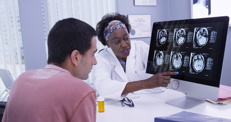 Close up of senior African doctor explaining to young patient his ct-scans of cranium. Intelligent...