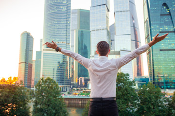 Back view of businessman looking on copy space while standing against glass skyscraper