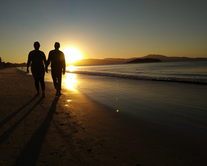 Fototapeta na wymiar couple walking on the beach at sunset