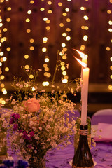 Party table decorated with lights in the background and candles