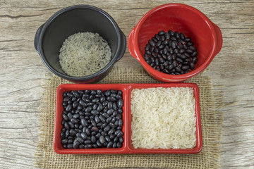 rice and black beans crude in red container on wooden background
