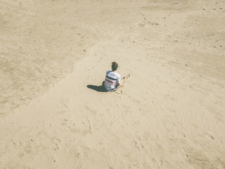 top aerial view of young hipster sitting on the abstract sandy sea beach. summer exotic concept d
