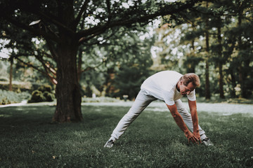 Man in White Sportswear Doing Exercises in Park.