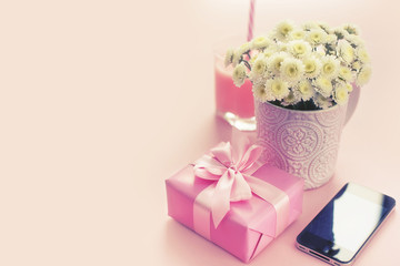 Composition flat lay gift to a woman Modern gadget mobile phone glass cocktail bouquet of flowers Preparing for the holiday surprise gift box Top view pink background toning
