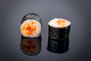 Maki with spicy salmon on black with reflection
