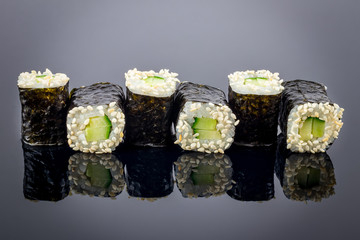 cucumber maki on black background with reflection