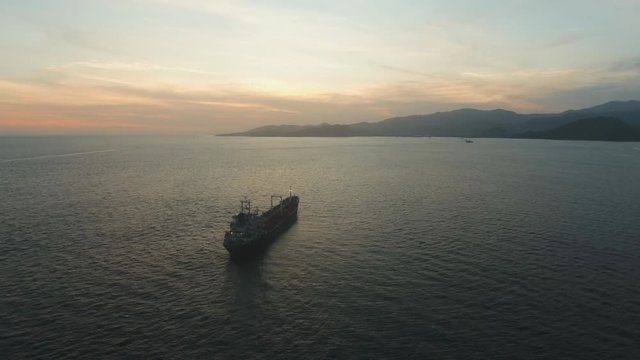 Aerial view Cargo ship in the sea at sunset. Sunset over the sea. Flying over the blue ocean with blue water, sky. Bali,Indonesia.4K video. Travel concept. Aerial footage