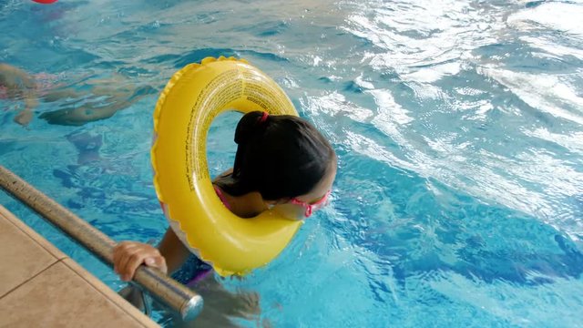 4k video of teenage girl playing and swimming with inflatable ring at swimming pool