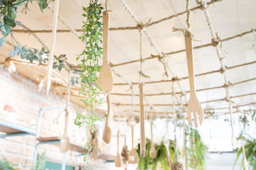 Kitchen utensils, a butcher's paddle, are hung by ropes. With decorative trees