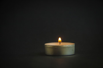Obraz na płótnie Canvas background of sorrows lonely candle on a dark black texture