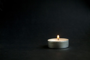Obraz na płótnie Canvas background of sorrows lonely candle on a dark black texture