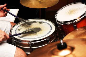 A drummer playing a snare drum with brushes.