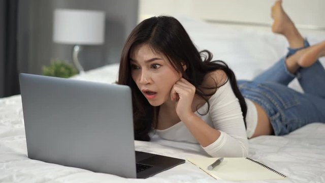 surprised woman using a laptop computer on bed