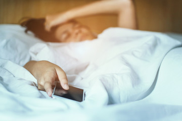 beautiful woman hates hand turns off smartphone alarm clock waking up at morning .get up early in the morning to work late.