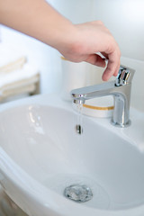 Male hand opening water tap or faucet in bathroom. Save water at home or water conservation concepts