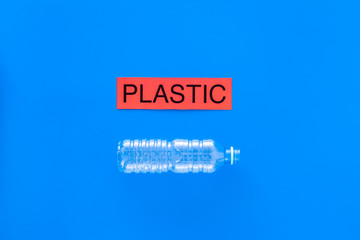 Waste suitable for recycle. Plastic bottle near word plastic on blue background top view copy space