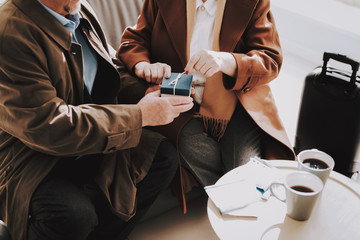 Smiling Man Giving Gift to Happy Woman in Airport.