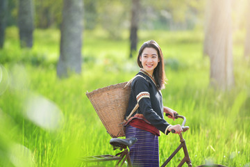 Traditional Hmong girl with basket of agricultural crops walking with bicycles in forest Happy...