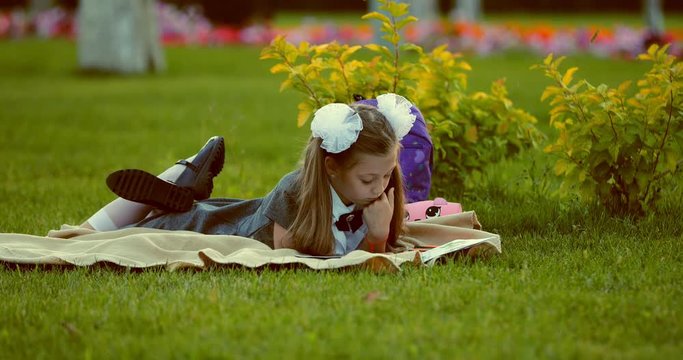Little beautiful girl scrolls album with drawings on a plaid on the grass