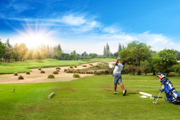 13-year-old Asian boy hit sweeping golf ball on a golf course in the sunrise, sunset time in holiday.