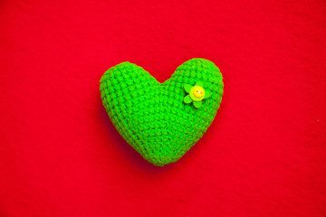 green knitted heart on a red background, a symbol of love to congratulate the holiday