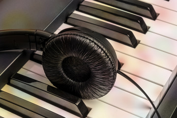 A photo of piano keys with headphones, recording music, toned image with a place for text