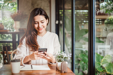 Young Asian beautiful woman using smart phone for business, online shopping, transfer money, financial, internet banking. in coffee shop cafe