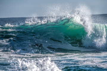 Turquoise blue wave breaking and spray
