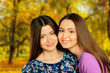 Obraz premium Two cheerful girls twins, in the street autumn park