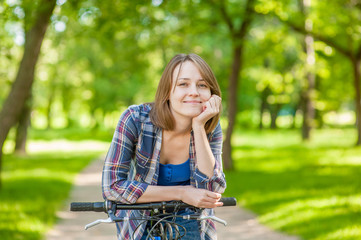 Fototapeta na wymiar Happy young beautiful woman riding a bicycle in a park