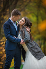 Bride in coat. Autumn wedding. Groom and bride portrait