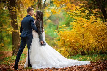 Groom and bride in autumn yellow leaves park. What to wear on the autumn wedding. Full length