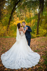 Groom and bride in autumn yellow leaves park. What to wear on the autumn wedding. Full length