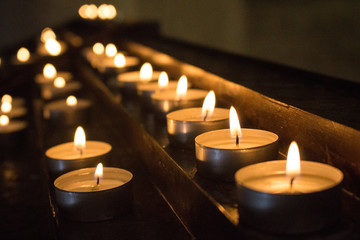 Rows of glowing candles in darkness. Candles with burning falme. Church decoration. Religion and faith background. Christmas eve decoration. Romance concept. Sorrow concept.
