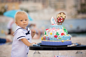 Sweet baby boy, celebrating on the beach first birthday with sea theme cake and decoration