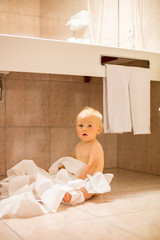 Toddler baby boy, ripping up with toilet paper in bathroom.